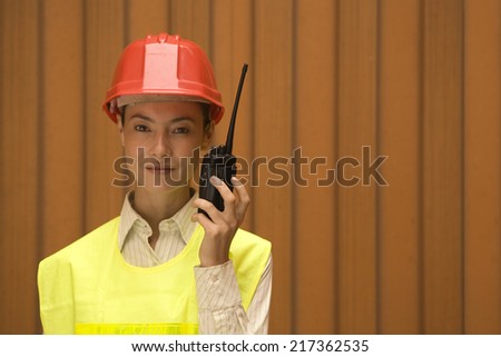 Portrait of a female dock worker talking on a walkie-talkie