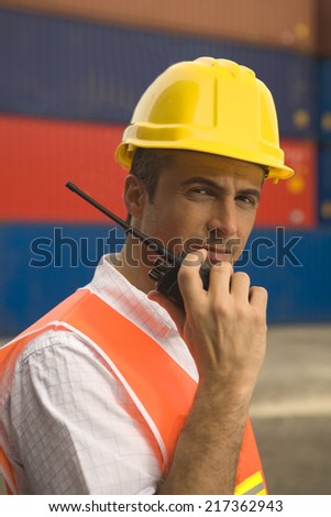 Portrait of a male dock worker holding a walkie-talkie