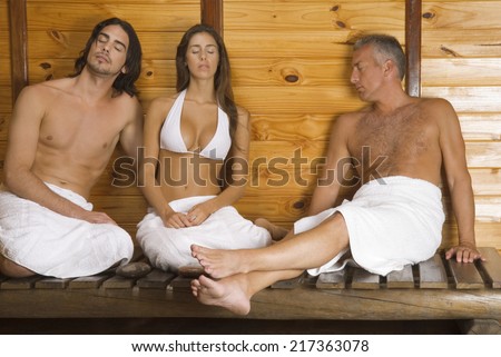 Young woman and a young man with a mature man having sauna