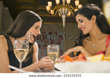 Young woman showing her engagement ring to her friend in a restaurant