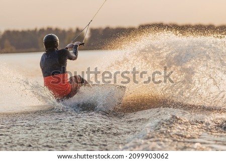 Wakeboarder making tricks. Low angle shot of man wakeboarding on a lake. Stock fotó © 