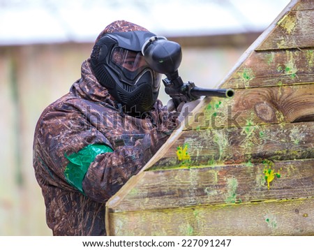 Man with paintball gun behind fortification with paint splashes