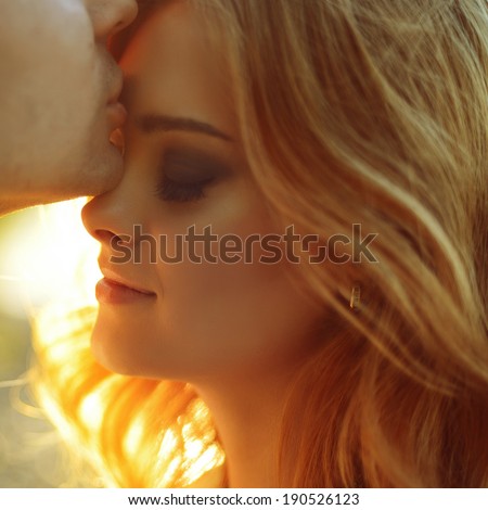 portrait of a beautiful girl and a guy kissing in the sun