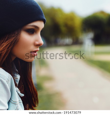 portrait of a beautiful girl in a cap and a denim jacket sitting and looking ahead