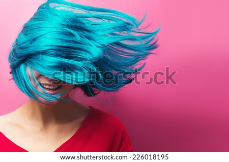 isolated studio portrait of a sexy beautiful girl with turquoise hair in motion on a pink background