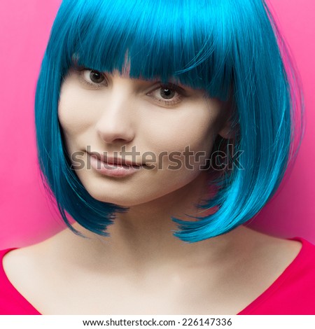 isolated studio portrait of a beautiful girl with turquoise hair on pink background with smile
