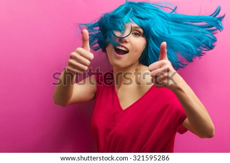 Sexy beautiful girl with turquoise hair in motion on a pink background. Isolated studio portrait.