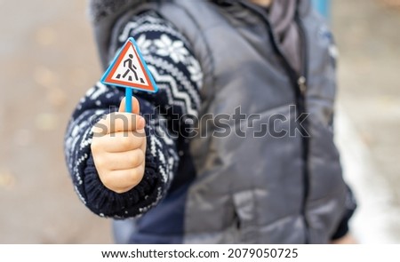 toy traffic sign in a kid's (boy) hand. plastic road sign with speed limit of 60 km per hour, crosswalk (zebra crossing) and road Sign Double Arrow Forward and To Turn Right.  Stok fotoğraf © 