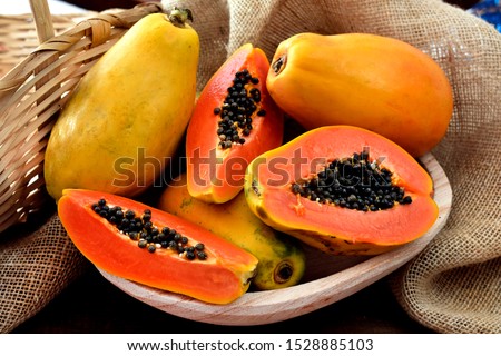 The papaya fruits in a wooden pot and a straw basket and rustic fabric at the background ストックフォト © 