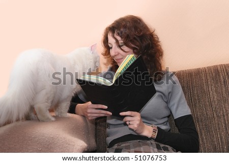 Casual woman reading at home. She looking at the white cat.