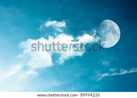 Moon between the clouds in dark night, a dark night brings a bright, amber moon alive with puffy hazy clouds.