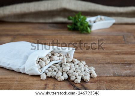 Sack with chickpeas and parsley on wooden table