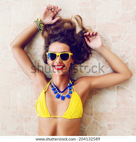 Happy pretty brunette woman smiling and having fun in hot summer day, wearing stylish neon bikini sunglasses and jewelry.