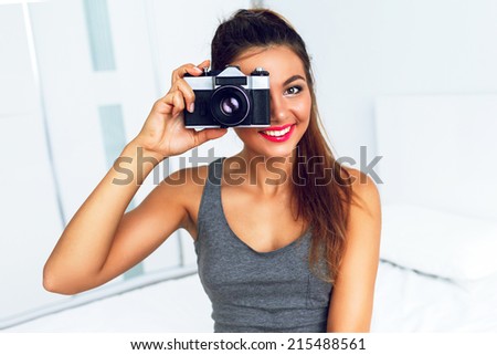 Close up fashion portrait of happy pretty smiling photographer girl making picture on old school retro camera, posing at big white too, with ponytail and plight make up.