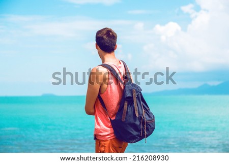 Young traveler looking on amazing view of clear blue ocean and mountains, enjoy amazing day and his freedom , man travel with backpack in Thailand .