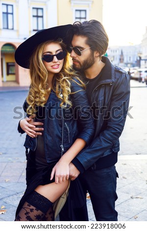 Fashion portrait of young sexy beautiful couple posing and hugs on the street, wearing trendy leather jackets, and vintage sunglasses. Outdoor fall trendy portrait of two lovers.