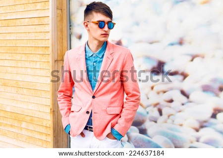 Outdoor fashion portrait portrait of young stylish hipster man, wearing trendy classic casual bright clothes and sunglasses, soft pastel colors.