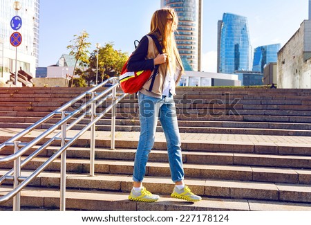 Outdoor fashion lifestyle urban portrait of young woman traveling with backpack, exploring new city. Wearing sportive bright casual outfit, nice sunny day.