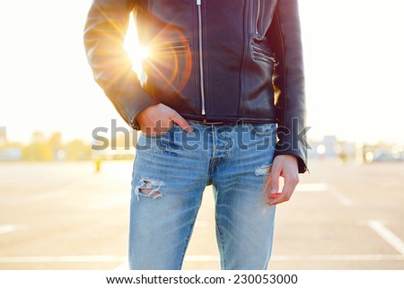 Fashion image of man posing at sunny day, wearing stylish leather jacket and jeans.