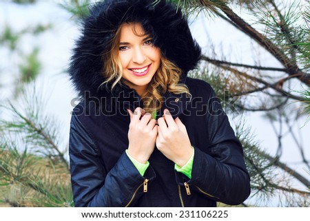 Close up lifestyle portrait of happy cheerful woman having fun alone at winter day, have red hairs bright make up and amazing smile.Wearing nice stylish jacket with fur, neon sweater. Holliday mood.