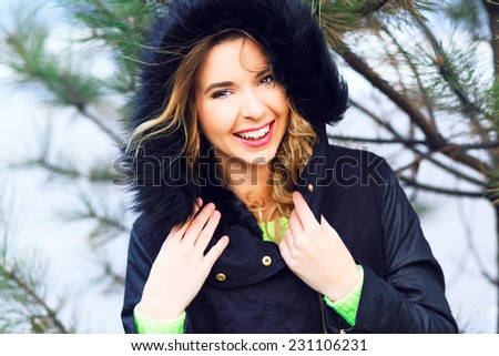 Close up lifestyle portrait of happy cheerful woman having fun alone at winter day, have red hairs bright make up and amazing smile.Wearing nice stylish jacket with fur, neon sweater. Holliday mood.
