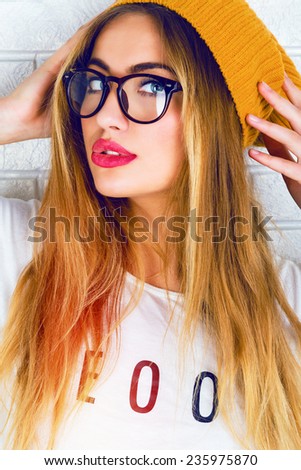 Close up bright fashion portrait of stylish hipster girl in glasses and hat, have sexy smile , full red lips and long blonde hairs, white background.