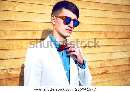 Portrait of stylish handsome hipster guy wearing official trendy suit and bow tie. Man fashion.  Natural wood background, bright sunny colors.