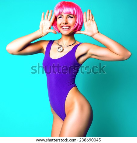 Fashion studio portrait of fitness model with perfect skin and body wearing sportive swimsuit carnival pink wig and massive diamond necklace. Crazy positive emotions mood, pastel sweet colors.