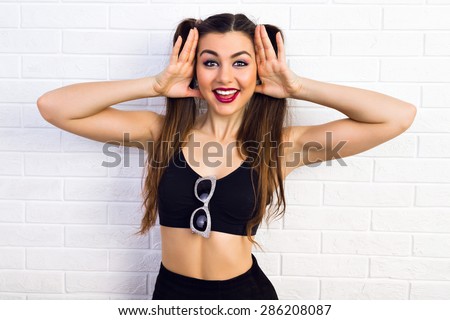 Gorgeous beauty. Beautiful young girl brown hair tied in a ponytail, holding hands near the face in a black top posing against white background.