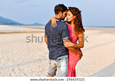 Amazing summer portrait of sensual couple hugs on lonely exotic beach, romantic atmosphere, evening sunlight.