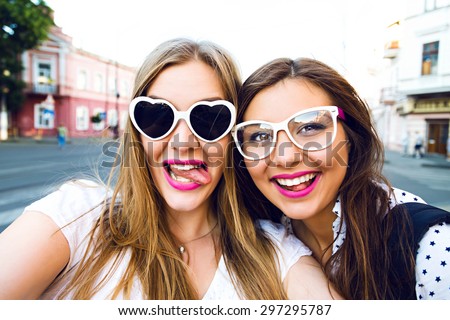 Cute outdoor portrait of funny pretty best friends girls having fun making selfie at city center, positive crazy emotions, traveling together in Europe, joy, vintage glasses, bright make up.