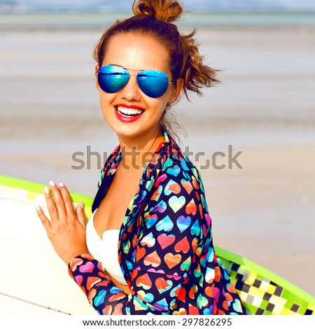 Outdoor lifestyle portrait of surfer girl posing at California beach, have perfect sportive tanned body, having active time at lonely exotic island, bright outfit, sunny colors. holding surf board.