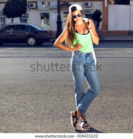 Outdoor fashion portrait of young teen hipster girl, street style swag look, hat, mom jeans, neon colors, travel at Europe.