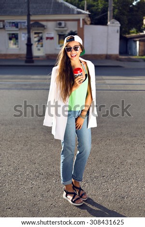 Outdoor fashion portrait of young teen hipster girl, street style swag look, hat, mom jeans, neon colors, travel at Europe.