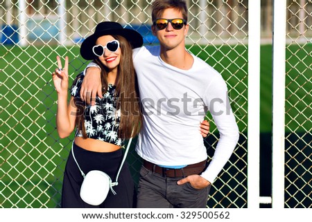 Young hipster couple having fun at summer time, hugs, emotions, wearing stylish black and white clothes and sunglasses, students party, joy, romantic.
