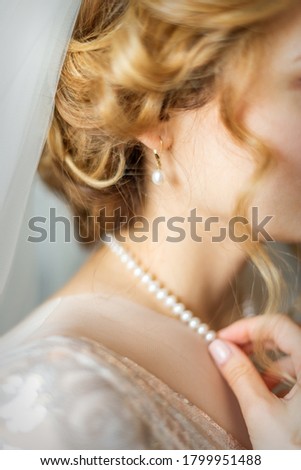 Beautiful caucasian young bride dresses necklace before wedding. Selective focus. Defocus. Blur.