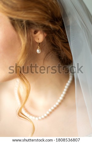 Wedding pearl earring on ear of beautiful caucasian young bride. Selective focus