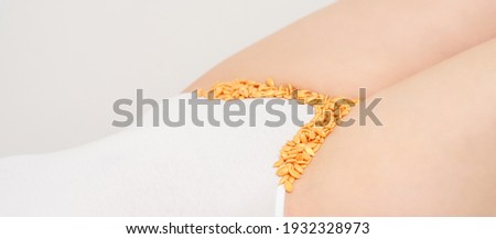 Depilation of the bikini area. Bikini zone of a young woman with wax hard beans lying down on a white background