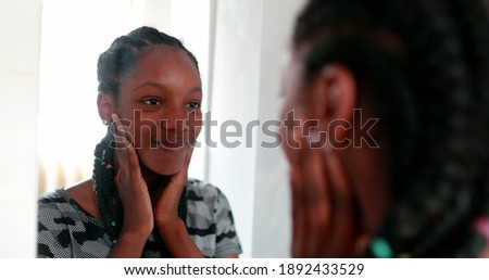 Confident teen adolescent black girl looking herself at mirror