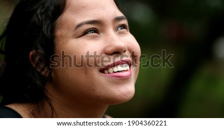 Latina girl looking at sky smiling. Hispanic young woman close-up face with HOPE and FAITH
