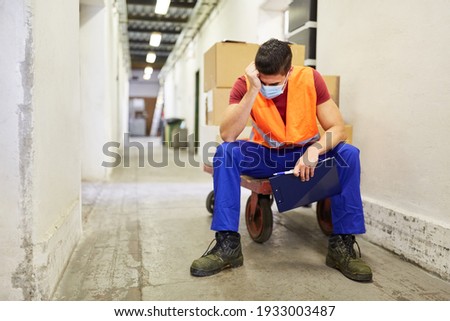 Stressed and exhausted worker with face mask because of Covid-19 in the warehouse Stock photo © 