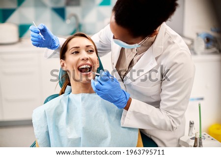 Young smiling woman having her teeth checked by dentist during appointment at dental clinic.