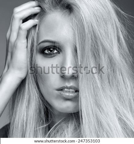 Monochrome portrait of blonde young woman on gray background