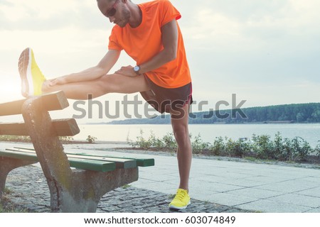 Urban jogger stretching / exercising on the bench.