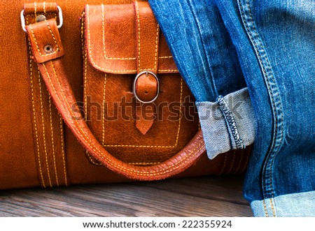 orange leather vintage suitcase travel bag and jeans on a wooden floor