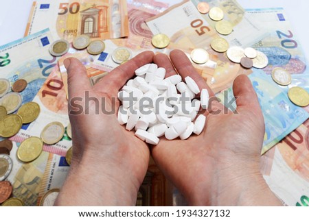 Hands  holding White pills on a background of money paper euro tickets and coins Foto stock © 