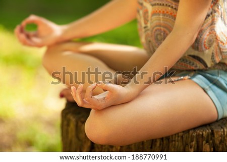 Young attractive female meditate in nature on beautiful summer day.