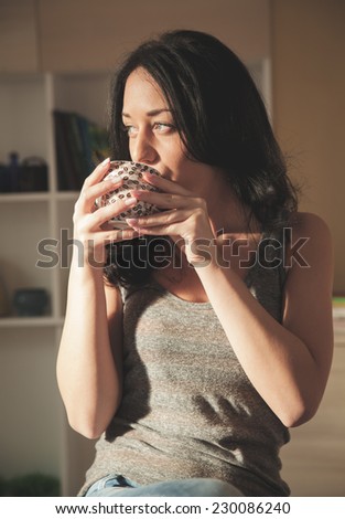 Young woman drinking coffee in living room.