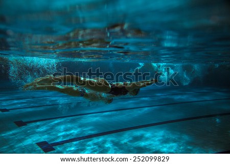 Two swimmers in swimming pool.Underwater image.Grain effect added for artistic impression.