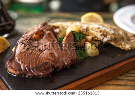 Grilled Tuna steak  with boiled potato and vegetables served on stone plate